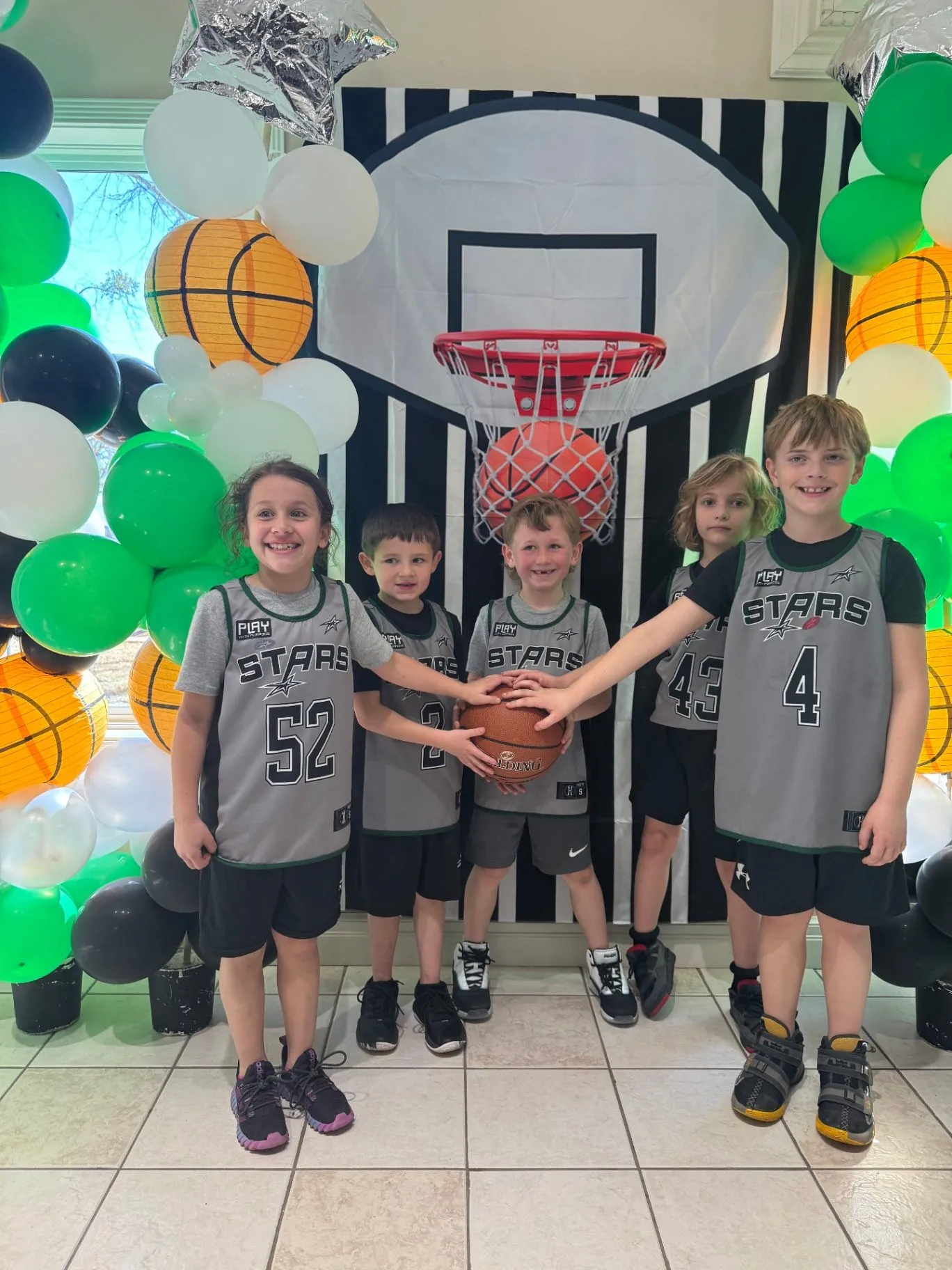 Green and gold balloon arch framing a lobby seating area with a paper chain garland